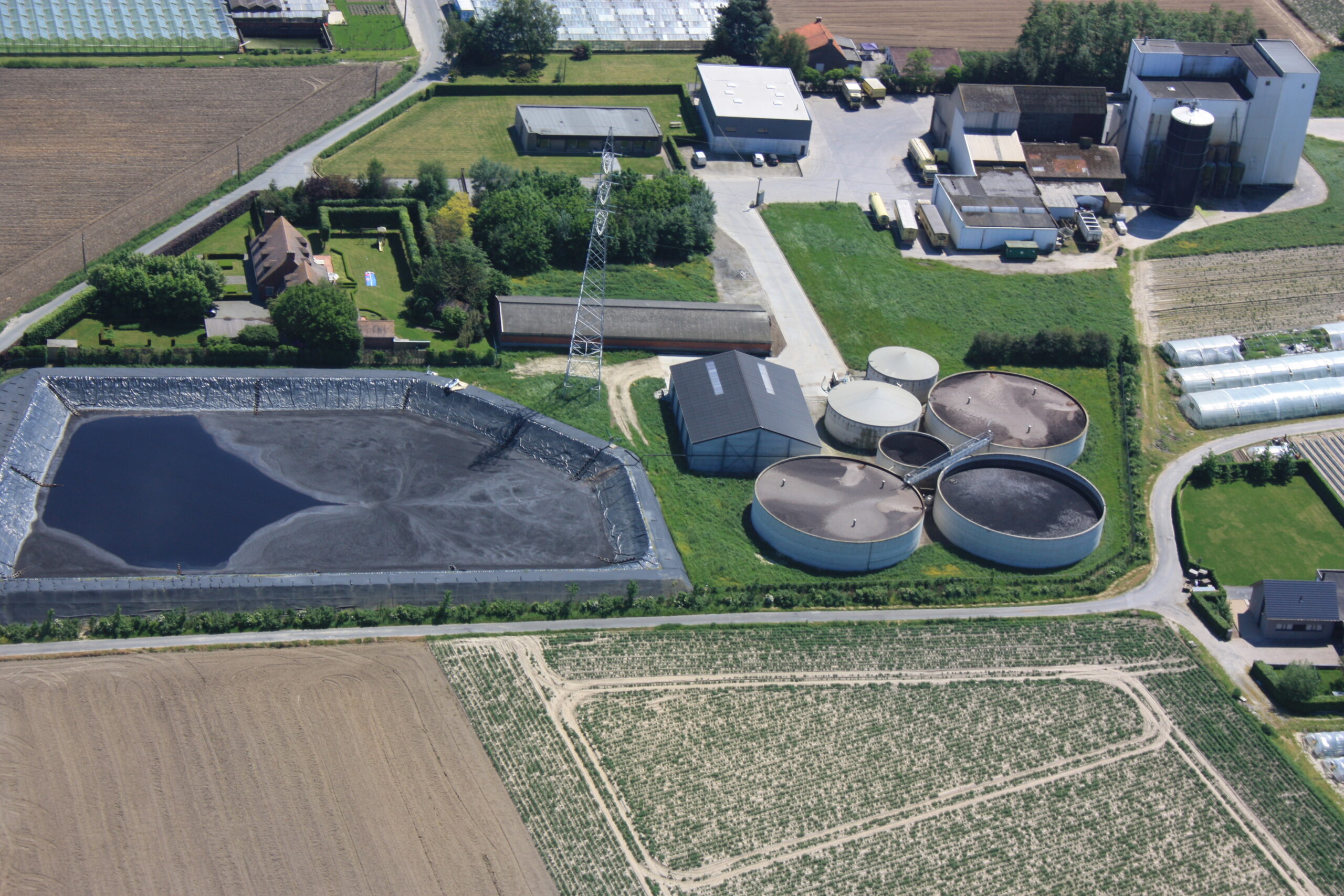Luchtfoto met links een foliebassin en rechts ronde betonnen opslagtanks