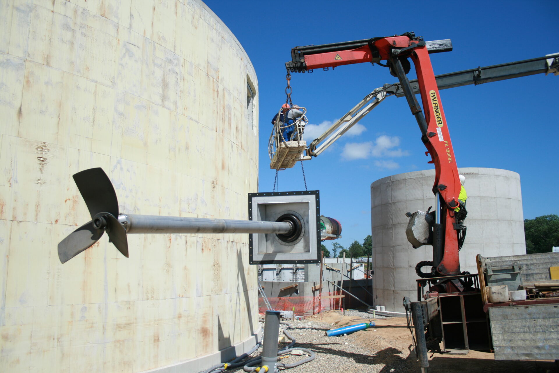Groot roerwerk met propeller dat met een kraan door de wand van een betonnen opslagtank wordt gemonteerd
