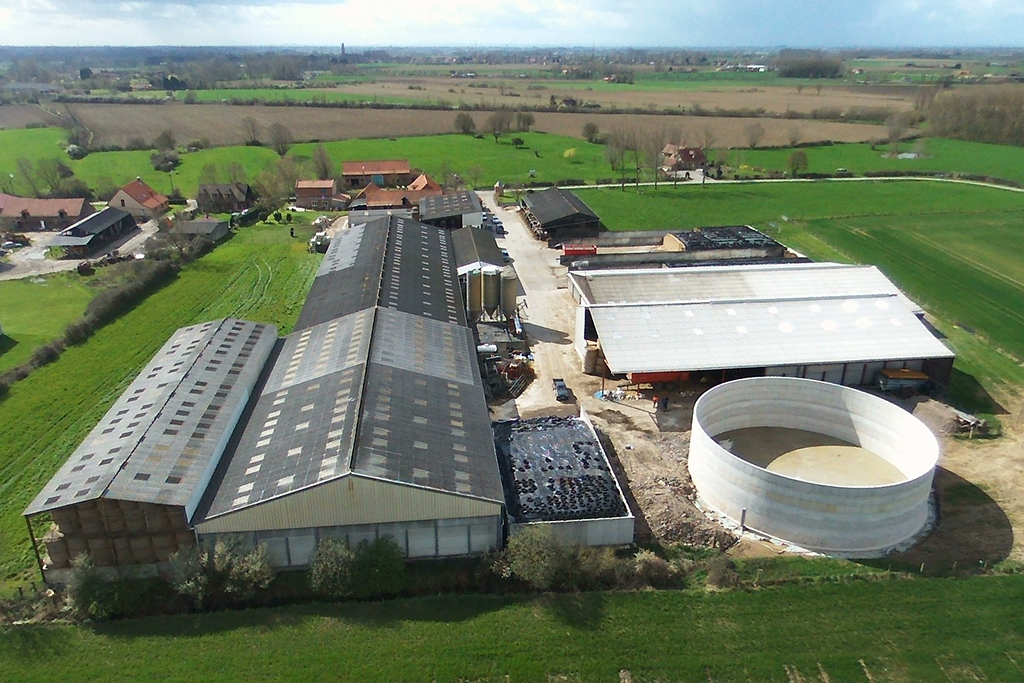 Luchtfoto van een agrarisch bedrijf met een nieuwe ronde betonnen mestsilo naast de stallen