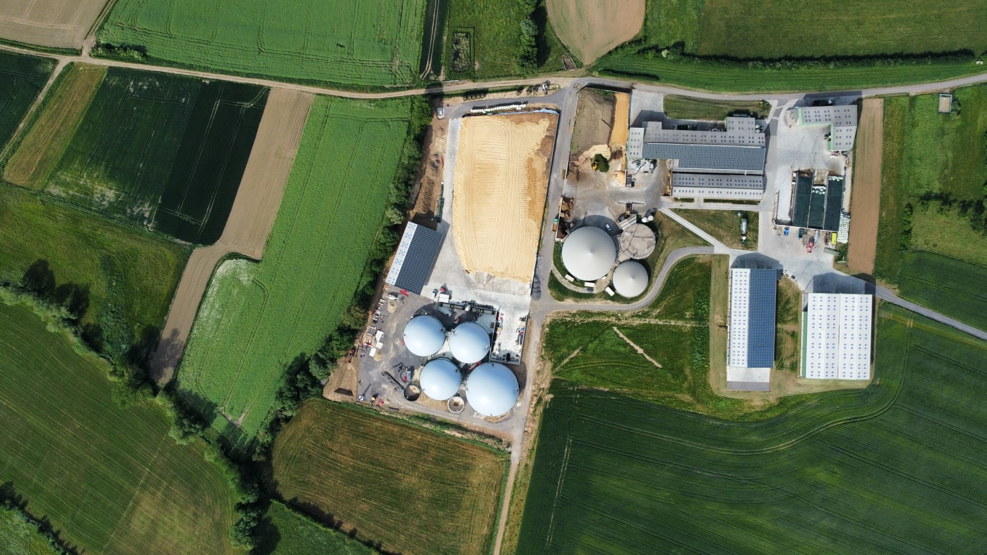 Luchtfoto van een bedrijfslocatie met ronde opslagtanks tussen de percelen